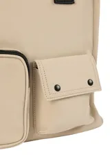 Bolso tipo tote color beige con doble asa superior negra y correa ajustable. Presenta un diseño estructurado con dos bolsillos frontales funcionales, uno con cierre y otro con solapa y broches a presión.