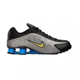 Championes Nike Shox R4 con parte superior en negro y plateado, diseño futurista con amortiguación de columnas azules en el talón y swoosh en tono amarillo.