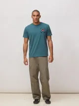 Remera de algodón orgánico color blanco, con corte regular fit y detalle de bordado en forma de X con diseño geométrico multicolor en el pecho.