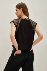 Remera de jersey de algodón grueso color crema, con mangas cortas y cuello redondo. Las mangas y el cuello son de microtul bordado con lentejuelas doradas.