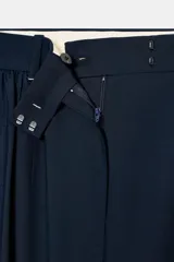 Pantalón de tiro medio color azul marino, de pierna ancha y caída fluida, con pliegues frontales y cintura con trabillas.