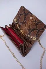 Cartera tipo sobre color beige con textura granulada y correa de cadena dorada.