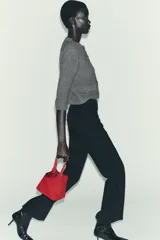 Chaqueta de punto grueso color gris, de cuello redondo y manga tres cuartos. Cierre frontal con botones joya dorados con detalles de pedrería. Cuenta con dos bolsillos frontales tipo parche.