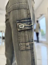 Pantalón cargo de jean azul claro, con bolsillos laterales tipo cargo en las piernas y bolsillos frontales aplicados, de corte ancho y holgado.