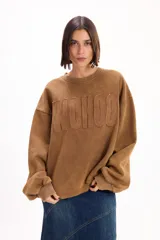 Buzo oversize color marrón con cuello redondo, mangas largas amplias y puños acanalados. Presenta letras en relieve con efecto desflecado en el frente y ruedo con terminación desflecada.