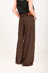 Pantalón de lino marrón, de tiro alto y corte wide leg, con bolsillos delanteros y cierre frontal de botón y cremallera.