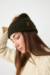 Gorro tipo beanie de punto acanalado en color verde oscuro, con doblez en el borde y pequeña etiqueta de cuero sintético con logo.