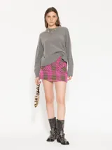 Minifalda de tweed con motivo pied de poule en fucsia y negro, de tiro alto con bolsillos frontales con solapa y botón dorado decorativo.