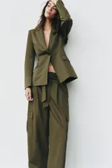 Blazer verde militar entallado con cuello de solapa, manga larga, cierre frontal de un botón y bolsillos con solapa.