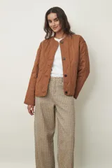 Campera acolchada color marrón claro, con cuello redondo, cierre frontal de botones y diseño de rombos.