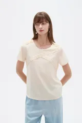 Blusa de viscosa color natural, con cuello a la base, manga corta y detalle de plisado cruzado en el frente. Presenta un corte holgado.