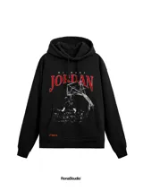 Hoodie negro de corte amplio con estampa frontal de Michael Jordan en acción y letras en color rojo. Cuenta con capucha con cordones ajustables, bolsillo tipo canguro y puños acanalados.
