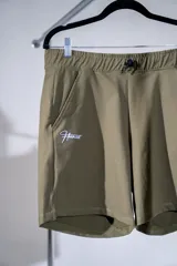 Short deportivo de poliamida y elastano en color verde militar, con cintura elástica ajustable mediante cordón, bolsillos laterales y logo bordado en contraste en la pierna derecha.