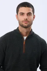 Buzo tejido de punto grueso en color azul marino, con cuello alto y cierre frontal parcial. Presenta detalles en gamuza en la zona del cierre y una textura en relieve en toda la prenda.