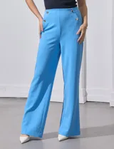 Pantalón naranja de crepe elastizado, corte recto, con bolsillos delanteros y apliques de botones metálicos.