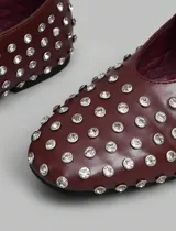 Balerinas color borgoña con apliques de strass plateados, tira sobre el empeine con hebilla plateada y punta redondeada.