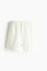 Short de denim liviano color blanco, de tiro alto con cintura elástica fruncida y cordón ajustable con detalles metálicos. Presenta corte holgado y bolsillos laterales discretos.