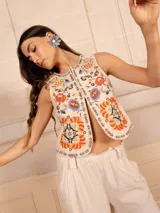 Chaleco color crema con bordados de flores de colores, sin mangas y con cierre frontal con botones.