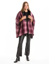 Ruana de tejido suave, color beige y marrón con estampado geométrico repetitivo. Posee cuello con aplique de piel sintética marrón y ribetes negros. Se combina con un suéter marrón de manga larga con botones en el puño.