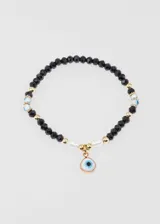 Pulsera elastizada con mostacillas negras, detalles de mostacillas doradas y celestes, y dije colgante de ojo turco con borde dorado.
