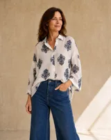 Camisa blanca de manga larga con estampado azul en contraste, cuello camisero y cierre frontal con botones.