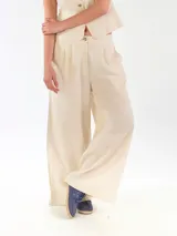 Pantalón de lino color beige, de corte ancho y relajado, con pretina elástica y cierre de botón.