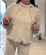 Canguro deportivo de tela suave con logo bordado, diseño holgado y mangas largas.