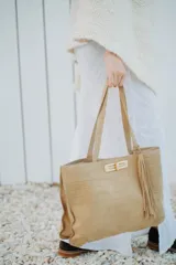 Cartera tipo tote de cuero con textura grabada tipo cocodrilo, color marrón. Cuenta con doble asa de hombro, cierre metálico frontal con detalle de borla y herrajes dorados.