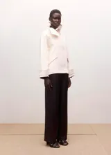 Pantalón de vestir color marrón oscuro, de corte recto y holgado, con tiro medio y diseño clásico de pernera ancha.