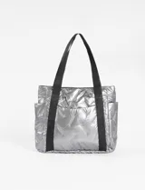Bolso tipo tote bag metalizado color plateado, con diseño acolchado y pespuntes en forma de rombos. Tiene doble asa de hombro color negro, bolsillos laterales y cierre principal.