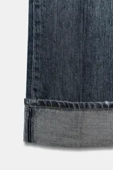 Pantalón de jean azul oscuro de corte recto, tiro medio, con bolsillos delanteros y traseros, trabillas para cinturón y ruedo doblado. Cierre frontal con cremallera y botón metálico.