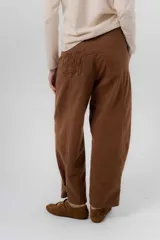 Pantalón de gabardina de algodón color negro, con calce barrel, cintura media baja, recortes de diseño y detalle de botones en el ruedo para ajustar el volumen.