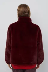 Chaqueta de piel sintética en color burdeos, con cuello alto y cierre frontal oculto. Presenta un diseño de corte recto y mangas largas con puños ligeramente ajustados.