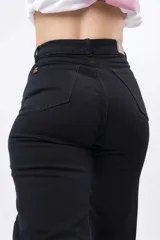 Pantalón de jean negro, corte Mom, tiro alto y calce relajado en piernas.