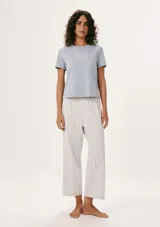 Pijama compuesto por una remera de manga corta color celeste con estampa frontal y un pantalón largo de corte recto con estampado de rayas verticales en tonos neutros.