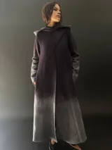 Tapado largo de lana merino color gris oscuro con teñido degradado en gris claro en ruedo, mangas y capucha. Tiene corte recto, bolsillos laterales y cierre cruzado con broches a presión ocultos en los hombros.
