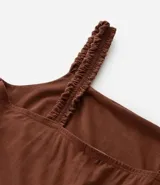 Vestido midi de algodón color marrón, con escote cuadrado y breteles anchos con detalle de volados. Presenta un corte imperio con elástico en la cintura y falda con recortes y volados en el ruedo.