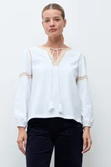 Remera de estilo boho color blanco, con mangas largas, escote en V con cordones y detalle de bordado en el pecho.