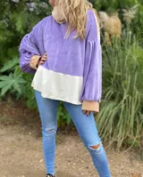 Polerón de corte holgado con mangas largas abullonadas, confeccionado en terciopelo negro con detalles en beige y blanco.