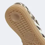 Championes Adidas Handball Spezial con diseño de estampado animal print tipo vaca en tonos marrón y blanco, con las icónicas tres tiras laterales en blanco, cordones celestes y suela de goma color caramelo.