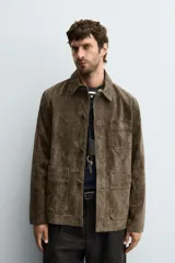 Sobrecamisa de corte regular confeccionada en piel con acabado serraje. Presenta cuello solapa, cierre frontal con botones y bolsillos de plastrón en el pecho y la parte inferior.
