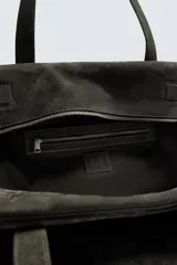 Bolso de viaje de gran tamaño confeccionado en piel con acabado de serraje. Cuenta con un compartimento principal con cierre de cremallera e imanes, interior con bolsillo con cierre y bolsillo plano, y dos asas de mano de piel.