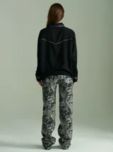 Camisa negra de algodón con mangas largas, cuello camisero y detalles de ribetes estampados a cuadros en los hombros, puños y aberturas de botones.