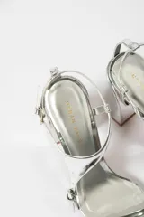 Sandalias plateadas de tacón bloque con tiras finas y cierre con hebilla en el tobillo.