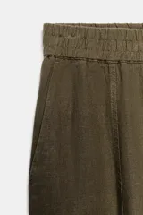 Pantalón de lino marrón oscuro, de corte barrel con pernera holgada que se estrecha hacia el tobillo, cintura elástica y bolsillos delanteros.