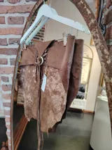 Top de cuero color marrón con diseño irregular y ajuste con cordones en la parte delantera.