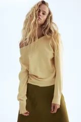 Buzo corto de punto fino suave color amarillo, con escote asimétrico y puños acanalados.