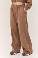 Conjunto deportivo de dos piezas compuesto por un buzo cropped de cuello alto con cordón ajustable y un pantalón estilo clochard de corte holgado con cintura elástica regulable y bolsillos laterales. Ambas prendas están confeccionadas en tejido técnico ligero con acabado suave al tacto.