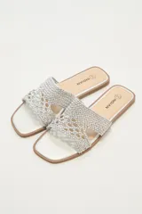 Sandalia plana marca Indian con capellada de tejido trenzado en color plateado y plantilla al tono con puntera cuadrada.