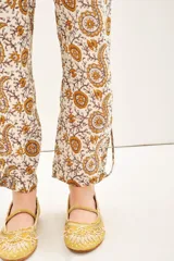 Babucha de voile de algodón con estampado tipo paisley en tonos tierra. Presenta un diseño holgado con lazos internos en el ruedo y botones para ajustar el largo.